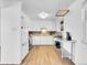Well-lit kitchen features white cabinets, stainless steel appliances, and light hardwood floors at 5225 Beech St, Arvada, CO 80002