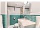 Bathroom features green tile, white vanity, and updated fixtures at 6051 Ivanhoe St, Commerce City, CO 80022