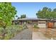 Charming brick home featuring solar panels, a well-kept yard, and an attached one-car garage at 6051 Ivanhoe St, Commerce City, CO 80022