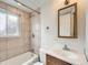 A bathroom showcasing the shower-tub combo, sink vanity, mirror and toilet with neutral tiling at 8267 High St, Denver, CO 80229