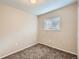 Simple bedroom showcasing neutral paint, carpet, and base trim with a bright window view at 8267 High St, Denver, CO 80229