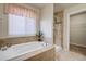 Bathroom with a large bathtub with tile surround and glass shower stall, complemented by a window and neutral tones at 6812 Indian Paintbrush St, Frederick, CO 80530