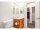 Well-lit bathroom with a wood vanity, tile flooring, and a doorway to a carpeted room at 7172 Kalamath St, Denver, CO 80221