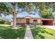 Charming brick home featuring mature trees, a well-manicured lawn, and a convenient carport at 7172 Kalamath St, Denver, CO 80221