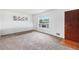 Bright living room with neutral carpet, a large window, and a classic wooden door at 7172 Kalamath St, Denver, CO 80221
