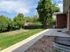 An angled view of the backyard with a concrete walkway, grass and trees at 1152 S Eaton St, Lakewood, CO 80232