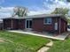 Brick home featuring a well-maintained backyard with lush lawn and concrete patio for outdoor enjoyment at 1152 S Eaton St, Lakewood, CO 80232