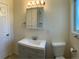 A bathroom with a sink and mirror with a toilet and a window at 1152 S Eaton St, Lakewood, CO 80232