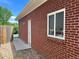 Side exterior view of red brick home with white trim window and door, concrete pathway and river rock at 1152 S Eaton St, Lakewood, CO 80232