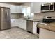 A bright kitchen with stainless steel appliances, granite countertops, white cabinets, and grey tile flooring at 1152 S Eaton St, Lakewood, CO 80232