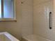 Updated shower with classic subway tile, grab bar, and natural light from a nearby window at 1152 S Eaton St, Lakewood, CO 80232