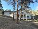 Two-story home on a hillside, featuring a large deck and natural landscaping with mature trees at 22148 Red Hawk Ln, Golden, CO 80401