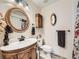 Charming bathroom featuring an ornate mirror, wood vanity, and a decorative moon mirror above the toilet at 11707 W 65Th Cir, Arvada, CO 80004