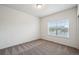 Empty bedroom featuring a large window with neighborhood views and neutral carpet at 56432 E 23Rd Ave, Strasburg, CO 80136
