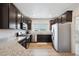 Modern kitchen features dark wood cabinetry, stainless steel appliances, and granite countertops at 56432 E 23Rd Ave, Strasburg, CO 80136