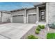 Three car garage with gray doors, stone accents, modern exterior, and manicured landscaping at 1465 Gentle Rain Dr, Castle Rock, CO 80109