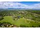 Expansive aerial view of lush green neighborhood with scenic mountain backdrop under a partly cloudy bright blue sky at 6982 Estes Dr, Arvada, CO 80004