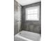 Bathroom with gray tile surrounding the tub and shower, accompanied by a bright window at 6982 Estes Dr, Arvada, CO 80004