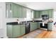 Updated kitchen features sage green cabinets, granite countertops, and stainless steel appliances at 6982 Estes Dr, Arvada, CO 80004