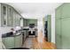Updated kitchen with green cabinetry, black countertops, and stainless steel appliances at 6982 Estes Dr, Arvada, CO 80004