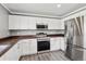 Modern kitchen with stainless steel appliances, white cabinets, dark countertops, and a stainless steel refrigerator at 9508 Elk Mountain Cir, Littleton, CO 80125
