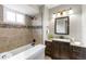 Updated bathroom features a bathtub with tiled walls and mosaic accents, a modern vanity, and a new light fixture at 7604 S Lamar Ct, Littleton, CO 80128