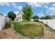 Spacious backyard with lush grass, a young tree, white fencing, and a gravel perimeter at 5572 Killarney St, Denver, CO 80249