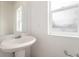 Simple, minimalist bathroom featuring a pedestal sink and two windows, offering ample natural light at 5572 Killarney St, Denver, CO 80249