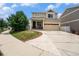 Two-story tan home featuring a two-car garage, manicured lawn, and inviting front entrance at 5572 Killarney St, Denver, CO 80249