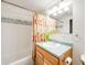 Bright bathroom featuring a colorful shower curtain, white tiles, and a wooden vanity with light green countertop at 683 Ridgemont Cir, Highlands Ranch, CO 80126