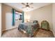Cozy bedroom with a paisley comforter, blue curtains and lighted ceiling fan at 683 Ridgemont Cir, Highlands Ranch, CO 80126