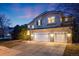Stunning two-story home with a three-car garage and stone accents, illuminated by warm exterior lighting at dusk at 683 Ridgemont Cir, Highlands Ranch, CO 80126