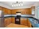 Well-lit kitchen featuring wood cabinets, black appliances, and dark countertops at 18508 E Whitaker Cir # D, Aurora, CO 80015