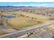 Expansive aerial view of a community park with a pond, open fields, and mountain views in the background on a sunny day at 5537 Lewis Ct # 1, Arvada, CO 80002