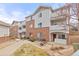 Brick and gray-sided condo with a red front door, small porch and landscaped yard at 5537 Lewis Ct # 1, Arvada, CO 80002