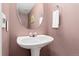 Cozy bathroom with pedestal sink, round mirror and pink walls at 3780 S Quemoy Way, Aurora, CO 80018