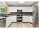 Kitchen with white cabinets, stainless steel appliances, and hardwood floors at 3780 S Quemoy Way, Aurora, CO 80018