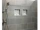 Modern walk-in shower featuring gray tiling, brushed nickel fixtures and a built-in shower niche at 2210 S Vaughn Way # 103, Aurora, CO 80014
