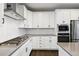 Modern kitchen with stainless steel appliances, white cabinetry, and herringbone tile backsplash at 11350 W Grand Ave, Littleton, CO 80127