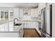 Bright kitchen features white cabinets, stainless steel appliances, dark wood floors, and island with sink at 11350 W Grand Ave, Littleton, CO 80127