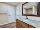 Bathroom with single sink vanity, granite counters, and framed mirror at 20964 E Greenwood Pl, Aurora, CO 80013