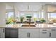 Kitchen island with double sink, white cabinets, and views to backyard at 8263 Merryvale Trl, Parker, CO 80138