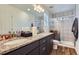 Bathroom featuring double sink vanity with granite countertop and tiled walk-in shower with glass door at 13589 E 102Nd Pl, Commerce City, CO 80022