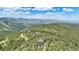 Breathtaking aerial view of a secluded home nestled amidst lush greenery and rolling hills against a picturesque mountain backdrop at 14980 Elk Mountain Trl, Littleton, CO 80127