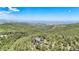 Expansive aerial view of a home nestled among dense trees, with city and mountain views at 14980 Elk Mountain Trl, Littleton, CO 80127