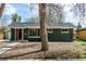 Charming single-story home with green brick, red door, mature trees, and a well-maintained front yard at 2702 Atchison St, Aurora, CO 80011