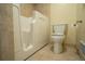 Close-up of a walk-in bathtub and toilet with light tan tiled walls at 3131 E Alameda Ave # 1604, Denver, CO 80209