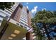 High-rise condominium building featuring brick and white facade under a sunny sky and mature trees at 3131 E Alameda Ave # 1604, Denver, CO 80209