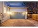 Well-lit garage exterior with a large door and a concrete driveway in front of a light-colored home at 2550 Xanthia Ct, Denver, CO 80238
