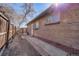 Side view of a brick home with a paved walkway leading to a back door and fenced yard at 2001 Grove St, Denver, CO 80211